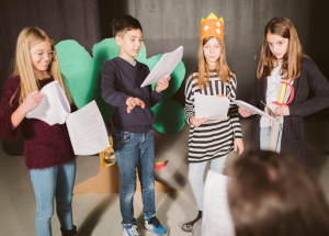 kids reading scripts on stage acting