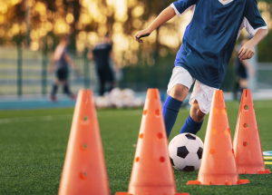 soccer player dribbling ball through cones
