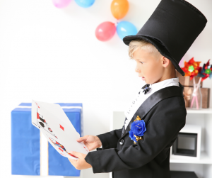 a child magician holding giant cards
