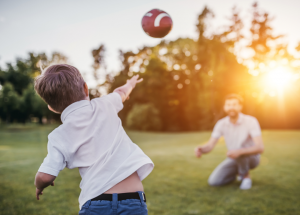 kid tossing football to parent