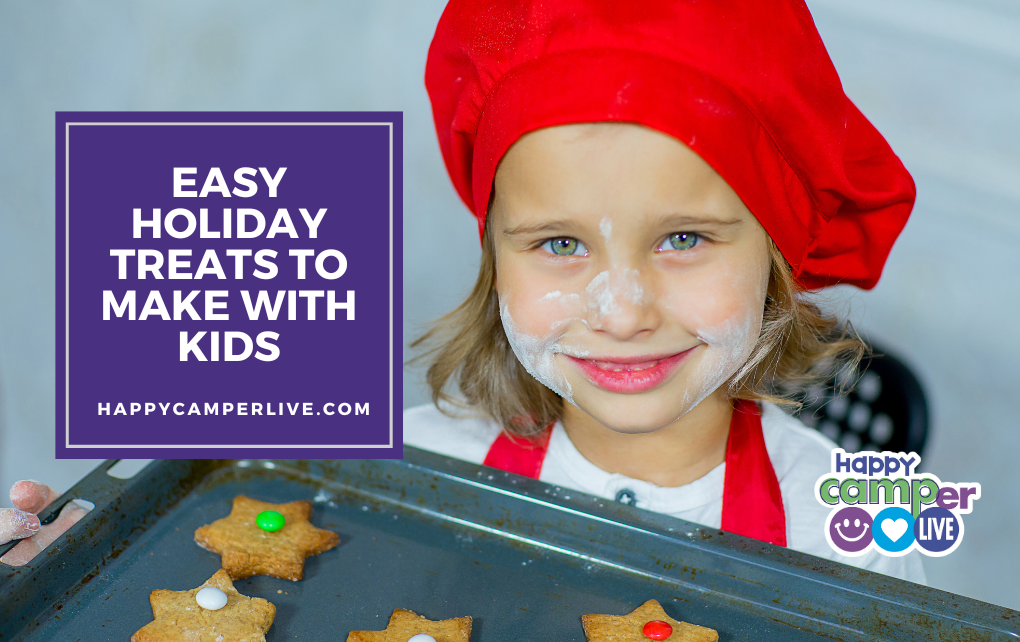 a child wearing a red bakers hat holds a tray of baked cookies