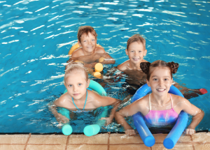 four kids in a pool with pool noodles