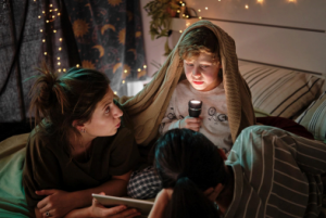 a kid holds a flashlight under their face