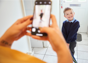 a parent uses a cell phone to take a first day of school photo